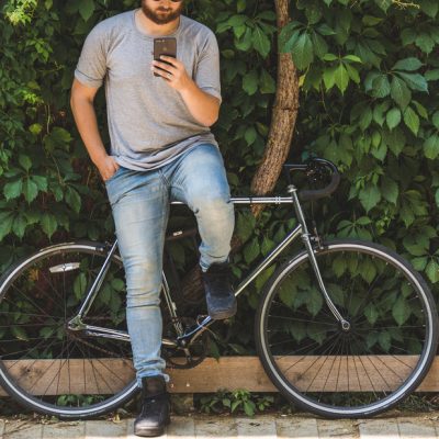 bike-and-phone Guy reading cellphone while pausing with his bike - email segmentation concept